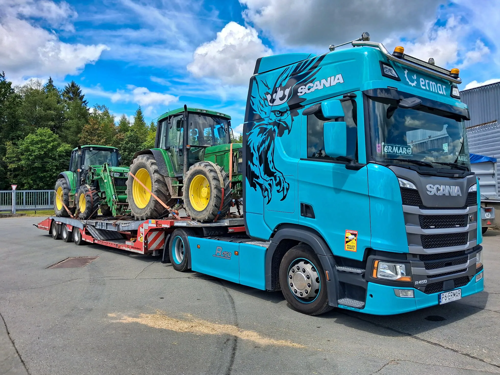 Dwa ciągniki John Deere na naczepie niskopodwoziowej ERMAR